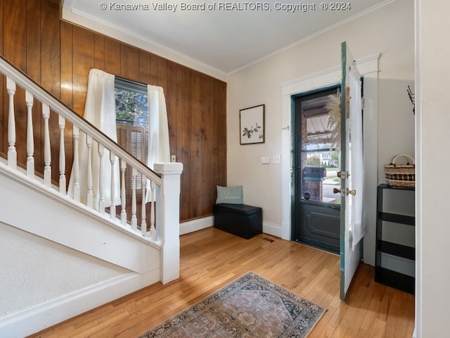 foyer entrance with crown molding, hardwood / wood-style flooring, and wooden walls