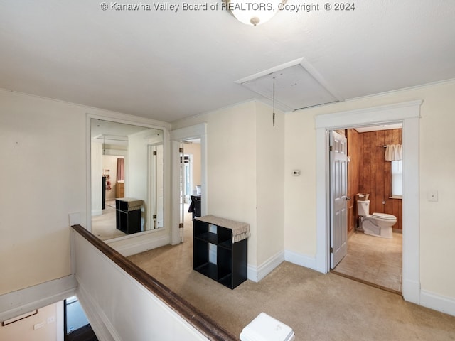 hallway with light carpet, ornamental molding, and wooden walls