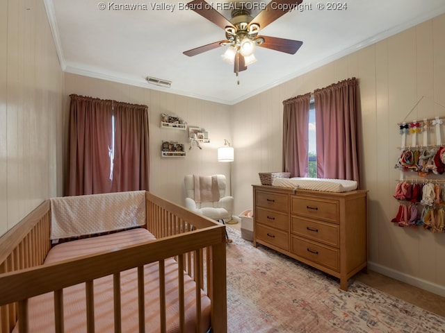 bedroom featuring crown molding, a crib, and ceiling fan