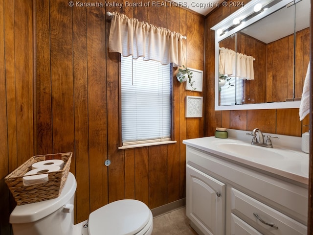 bathroom with vanity, toilet, and wood walls