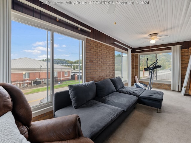 carpeted living room with ceiling fan and wood walls