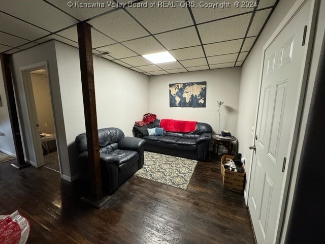 living room with a drop ceiling and dark hardwood / wood-style floors