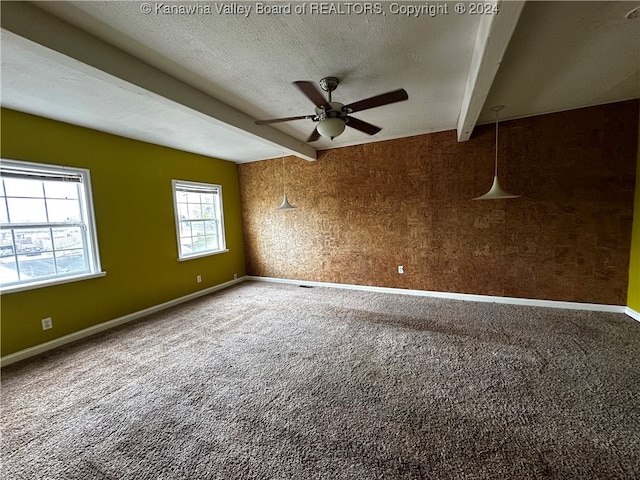 unfurnished room with beam ceiling, carpet flooring, a textured ceiling, and ceiling fan