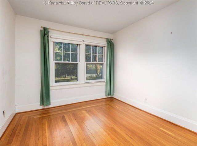 empty room featuring wood-type flooring and baseboards
