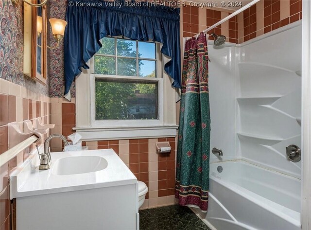 full bath featuring toilet, vanity, tile walls, wainscoting, and shower / tub combo