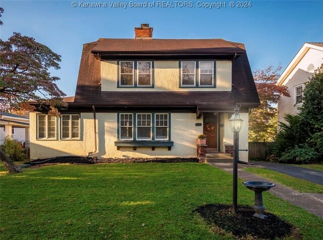view of front facade featuring a chimney, a front lawn, and stucco siding