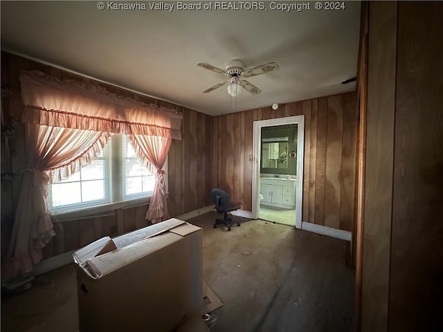 miscellaneous room featuring ceiling fan, wood walls, and concrete floors