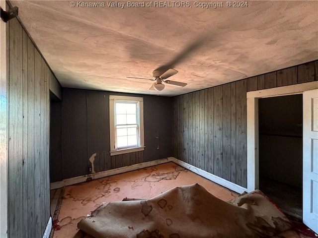 interior space featuring wooden walls and ceiling fan