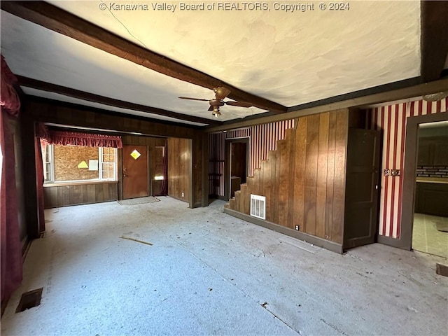 3962 39th St E, Nitro, WV 25143 - unfurnished living room with wood walls, a ceiling fan, beamed ceiling, and stairs