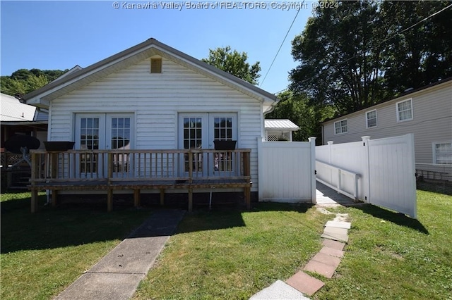 back of house with french doors, a deck, and a lawn