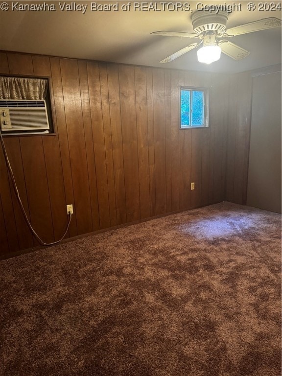 carpeted spare room with wooden walls and ceiling fan