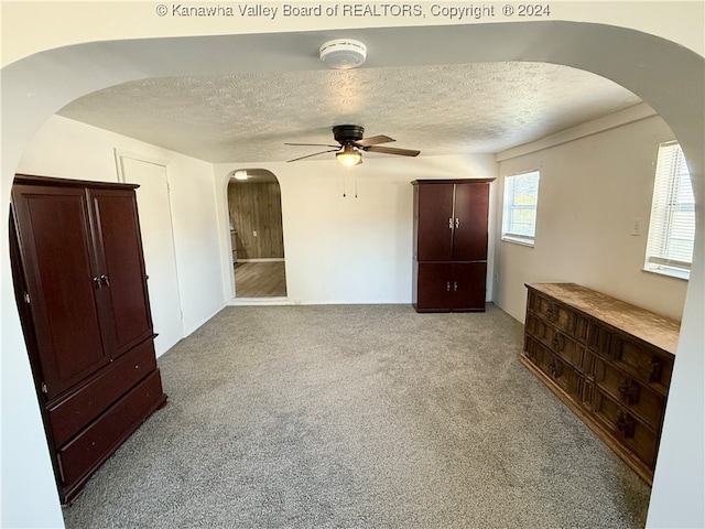 unfurnished bedroom featuring ceiling fan, a textured ceiling, and light colored carpet