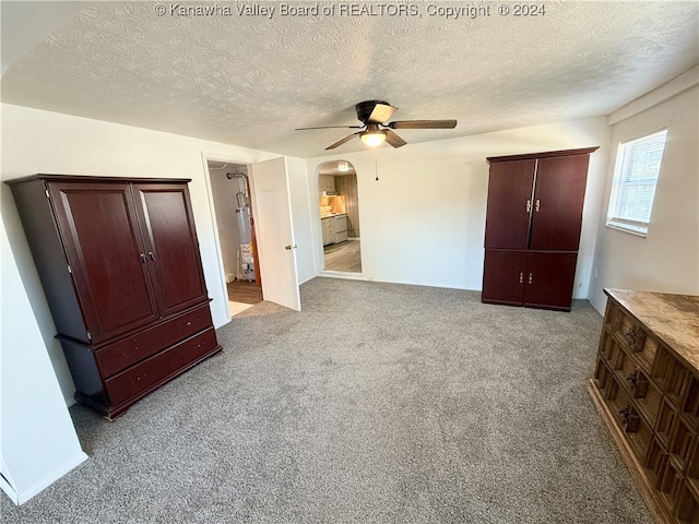 unfurnished bedroom featuring gas water heater, light carpet, a textured ceiling, and ceiling fan