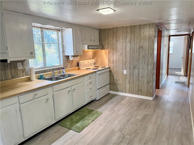 kitchen featuring wooden walls, sink, light wood-type flooring, white electric stove, and white cabinets