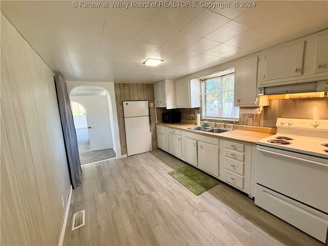 kitchen featuring sink, light wood-type flooring, white cabinetry, white appliances, and wood walls