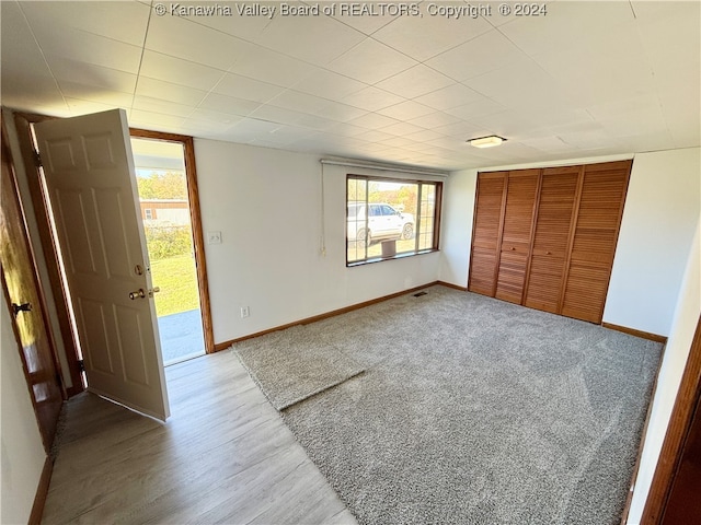 unfurnished bedroom with a closet, wood-type flooring, and multiple windows