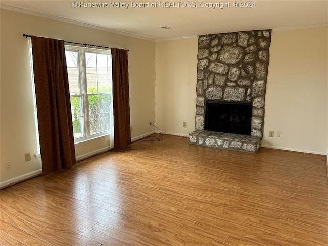 unfurnished living room featuring a fireplace, ornamental molding, and light wood-type flooring