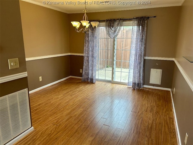 spare room featuring hardwood / wood-style flooring, ornamental molding, and a chandelier