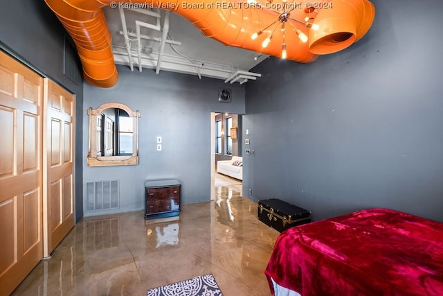 bedroom with a closet, a towering ceiling, and concrete flooring