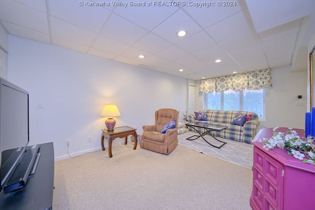 carpeted living room featuring a drop ceiling