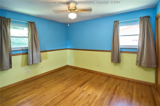 empty room with a healthy amount of sunlight, wood-type flooring, and ceiling fan