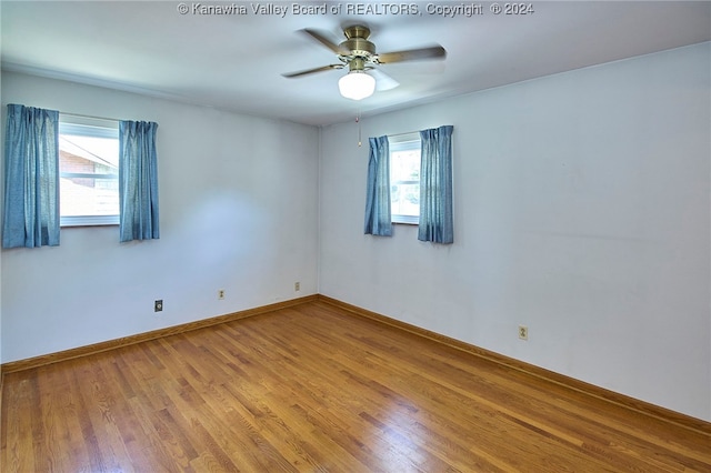 unfurnished room featuring a healthy amount of sunlight, wood-type flooring, and ceiling fan