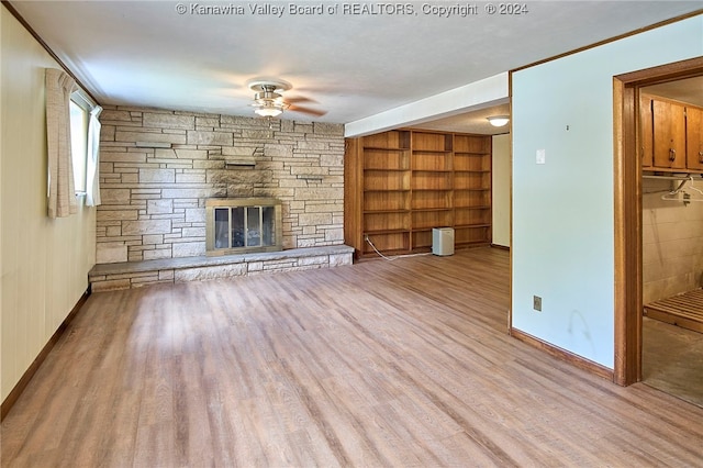 unfurnished living room featuring a stone fireplace, light hardwood / wood-style flooring, built in features, and ceiling fan