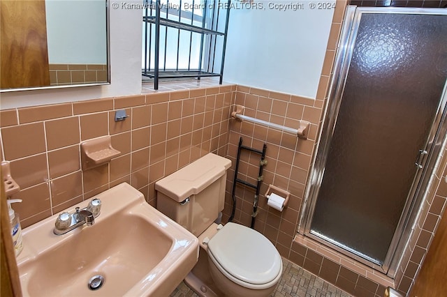 bathroom with tile walls, sink, toilet, and an enclosed shower