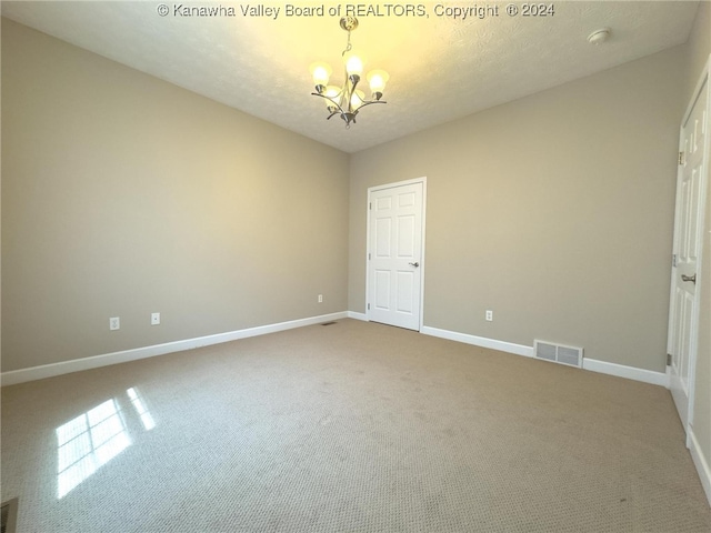 unfurnished bedroom with carpet, a textured ceiling, and an inviting chandelier