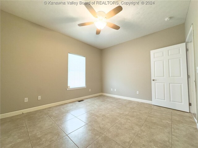 tiled spare room featuring ceiling fan