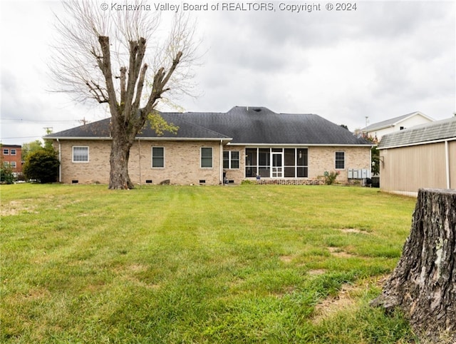 rear view of house with a yard and a sunroom