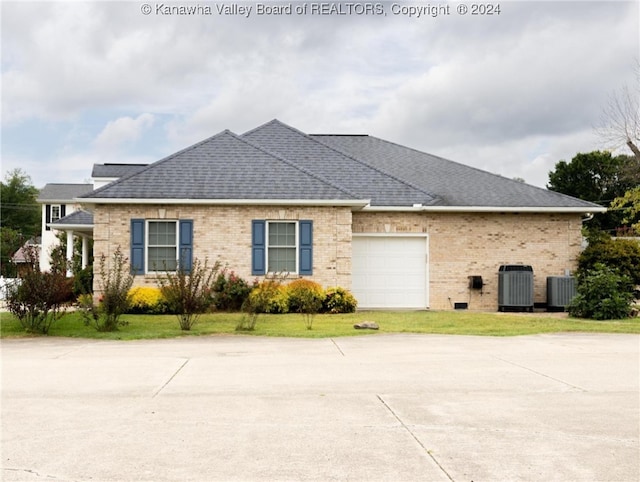 view of front of house featuring central air condition unit, a front yard, and a garage