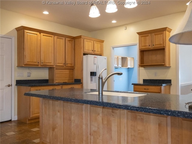 kitchen featuring sink, dark stone countertops, white refrigerator with ice dispenser, and hanging light fixtures