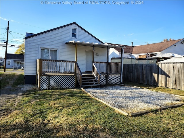 back of property featuring a deck and a lawn