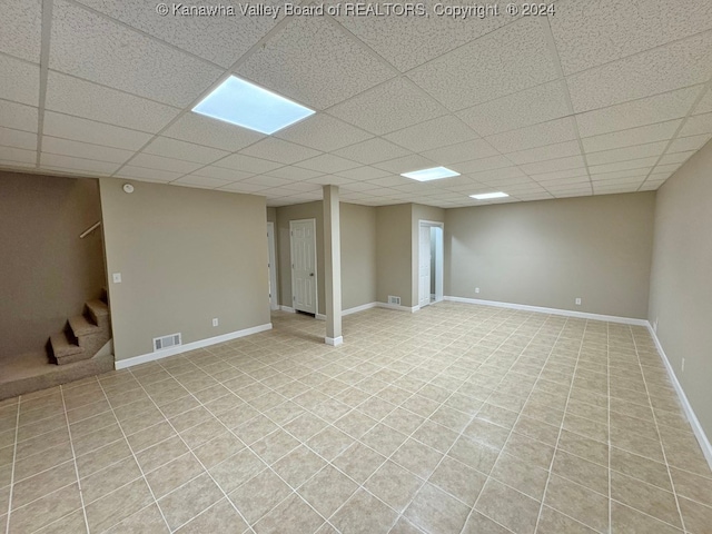 basement featuring light tile patterned floors and a drop ceiling