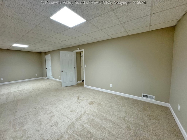 basement with a paneled ceiling and carpet flooring