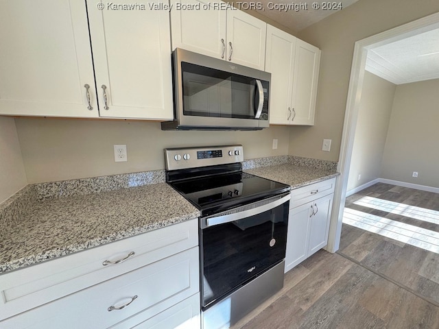 kitchen featuring light hardwood / wood-style flooring, white cabinets, stainless steel appliances, and light stone counters