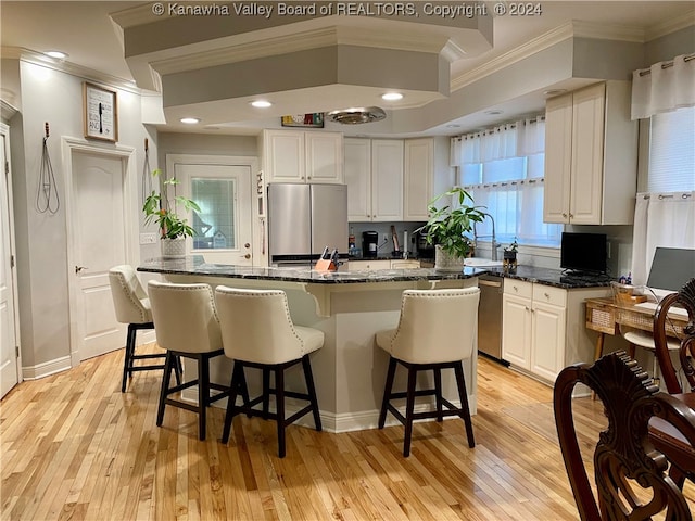 kitchen with white cabinetry, dark stone countertops, appliances with stainless steel finishes, and light wood-type flooring