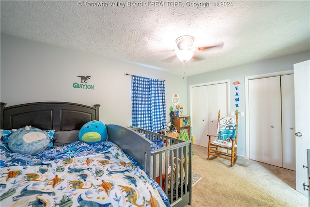 bedroom featuring ceiling fan, multiple closets, a textured ceiling, and carpet floors