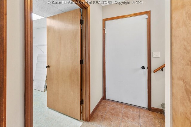 corridor featuring light tile patterned flooring and a drop ceiling