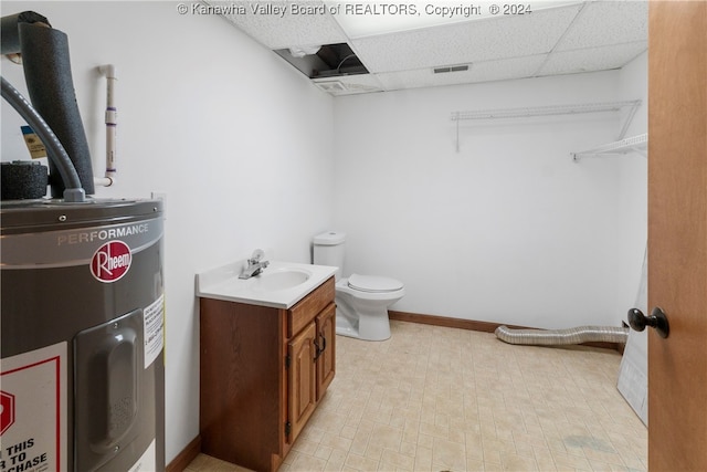 bathroom featuring vanity, water heater, a paneled ceiling, and toilet