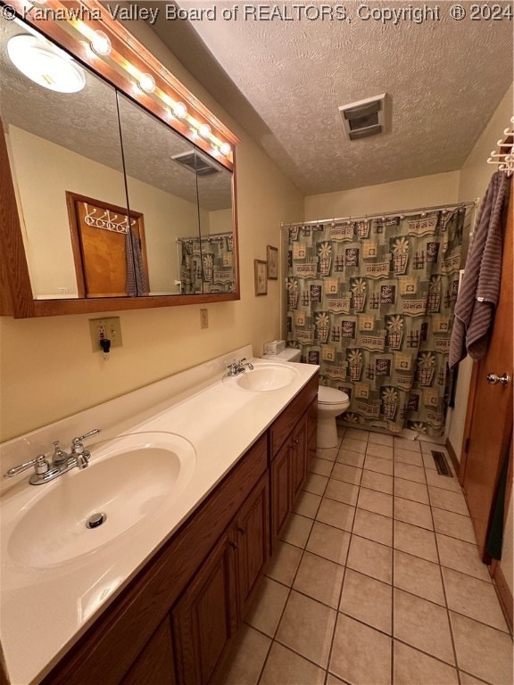 bathroom with a textured ceiling, walk in shower, toilet, vanity, and tile patterned floors