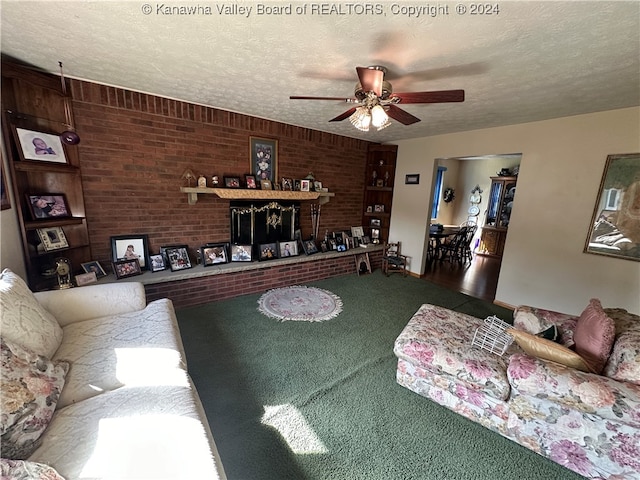 living room featuring ceiling fan, brick wall, and a textured ceiling