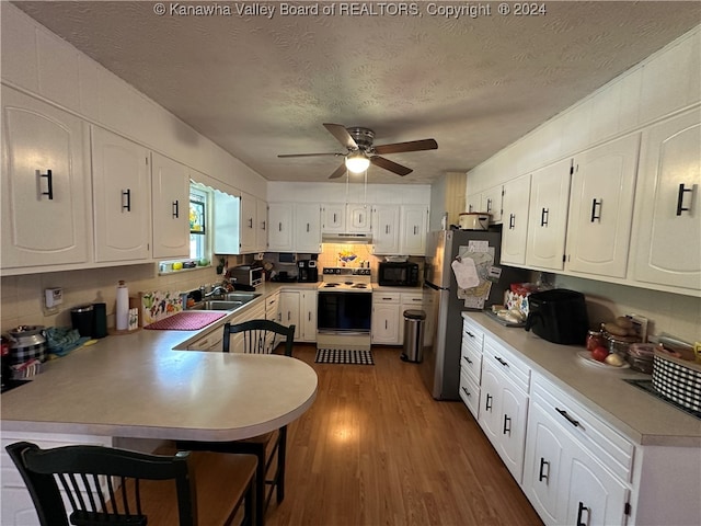 kitchen featuring white cabinets, white electric stove, a textured ceiling, and stainless steel refrigerator