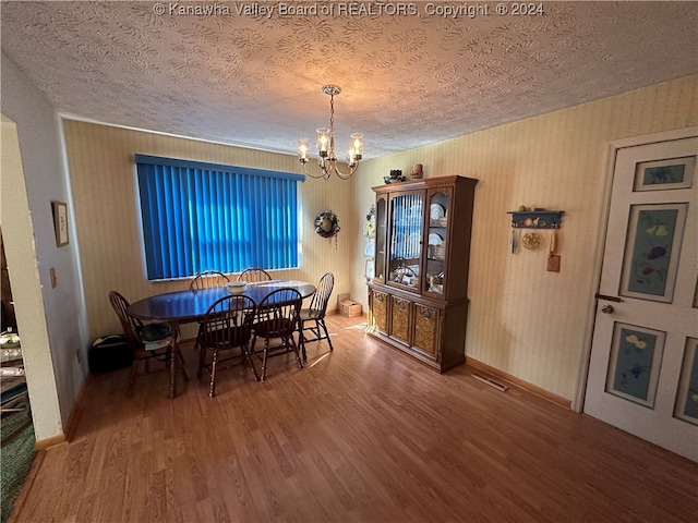 dining room featuring a textured ceiling, a notable chandelier, and wood-type flooring