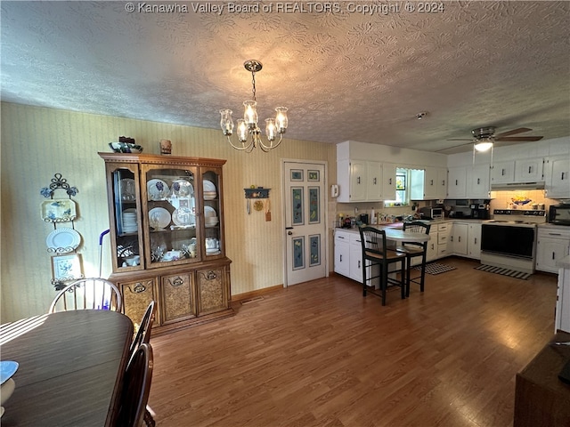 dining area with a textured ceiling, dark hardwood / wood-style floors, and ceiling fan with notable chandelier