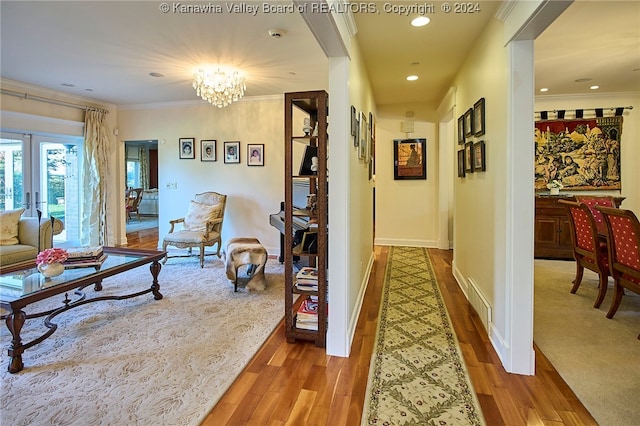 hall with crown molding, light hardwood / wood-style flooring, and a chandelier