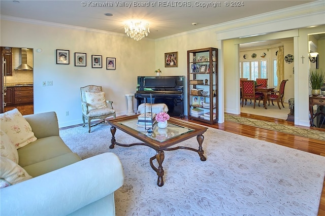 living room with ornamental molding, a notable chandelier, and light wood-type flooring