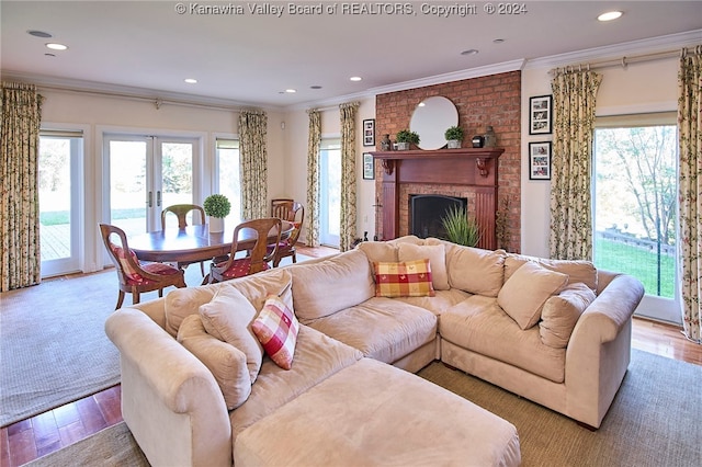 living room featuring french doors, ornamental molding, light hardwood / wood-style flooring, and a brick fireplace