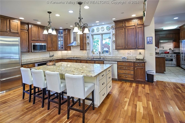 kitchen with light hardwood / wood-style floors, appliances with stainless steel finishes, a chandelier, and a kitchen island